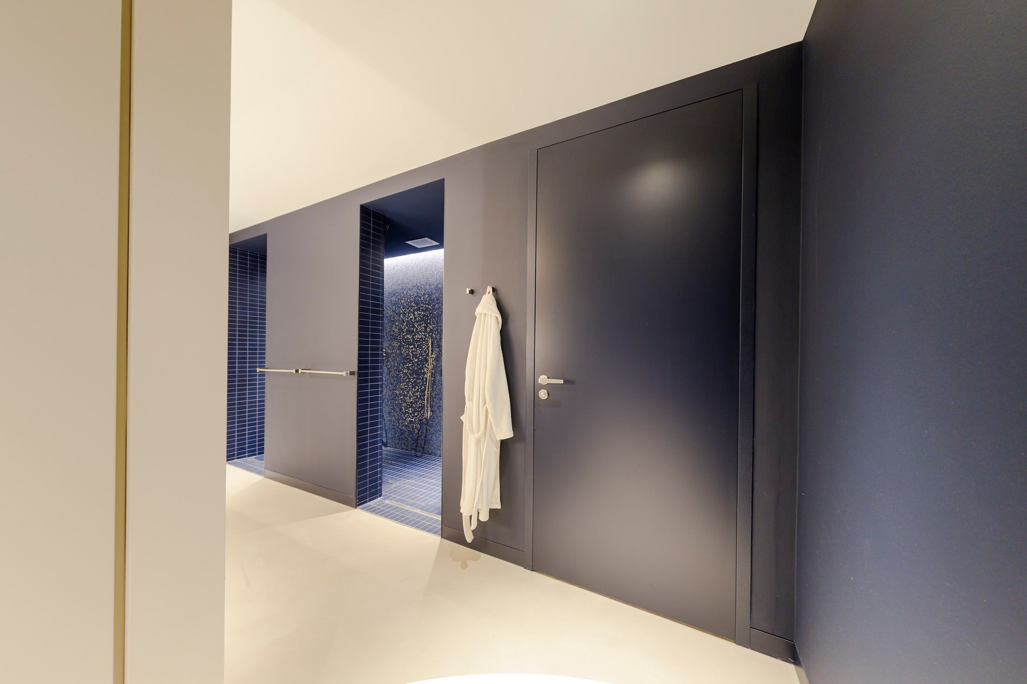 Lys mikrobetonggulv på badet med dusj og blå fliser på veggen moderne og stilfullt design